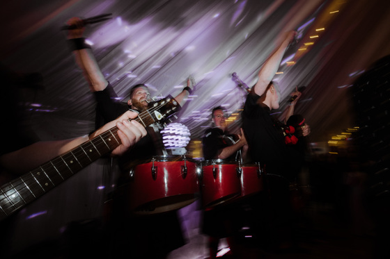 Action shot of wedding band performing with guitars and drums by White Heather Wedding & Event Planning Services